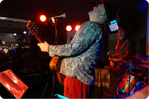 Singer plays acoustic guitar.